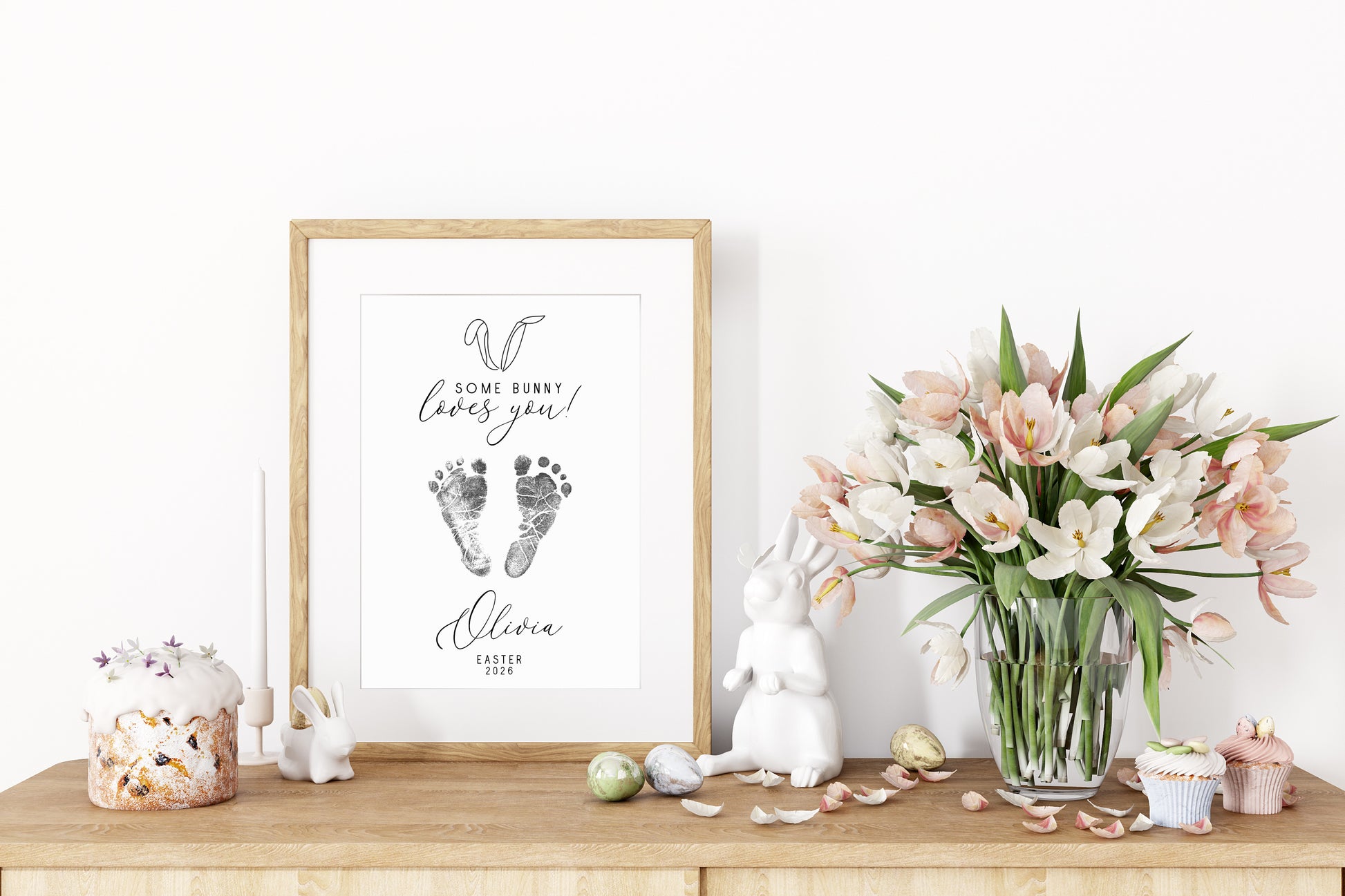 Framed keepsake with baby footprints on a wooden surface with decorative items.