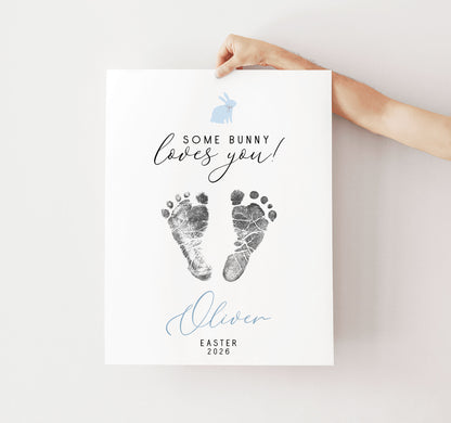 Hand holding a keepsake with baby footprints and text 'Some Bunny Loves You' on a light background
