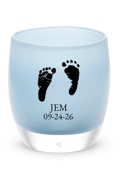 Glassybaby tea light holder with footprints and text on a white background