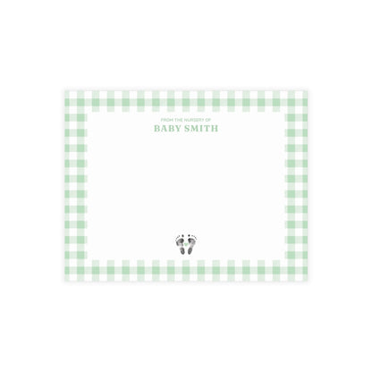 Green gingham border with baby footprints and text on a white card.