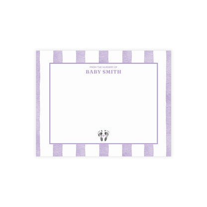 White card with baby footprints, orange and white striped border and text.