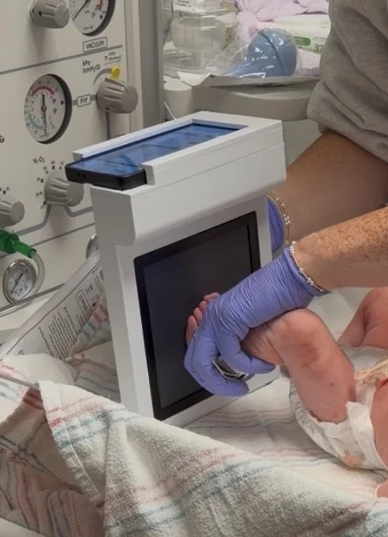 A hospital caregiver captures a newborn's footprint with the First Stamps scanner